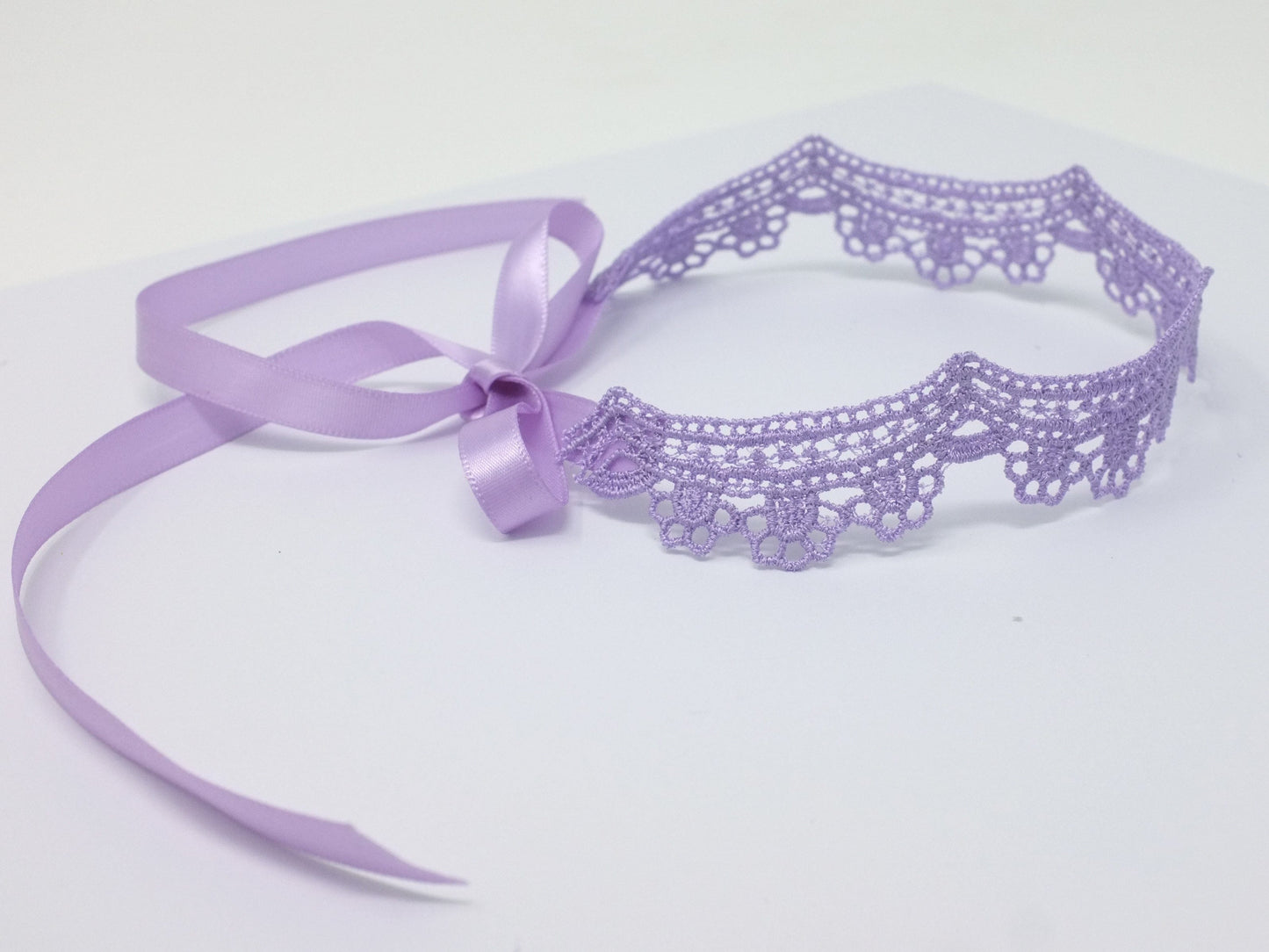 Lilac lace choker with floral scalloped design. The lace choker closure is a lavender satin ribbon