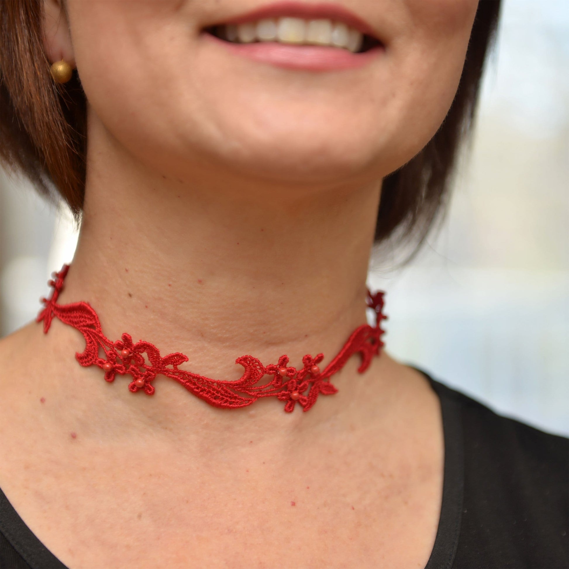 Lifestyle image of a woman wearing  a Red Lace Choker with red Pearls